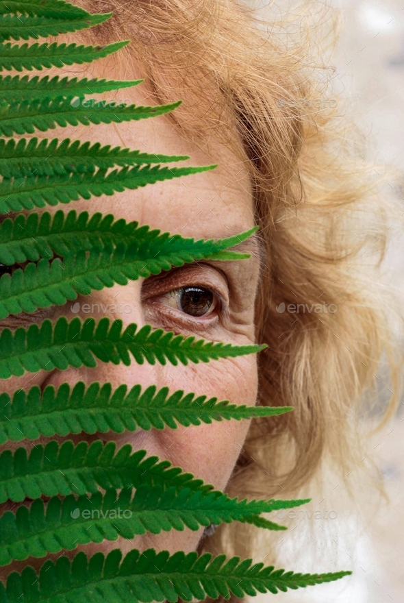 A portrait of a woman behind a green leaf, hide, looking away