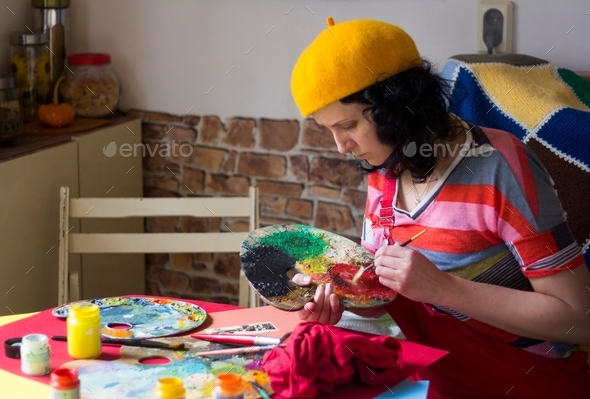 A woman painting on the table, colorful painting tools, palette on the table