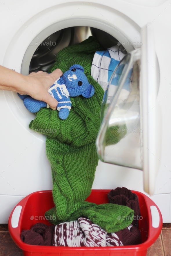 Removing washed clothes and toys from the washing machine Stock Photo by mirarahneva