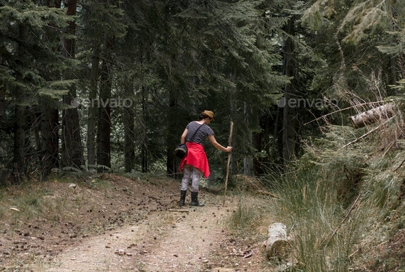 A woman walking in the wood, holding a stick