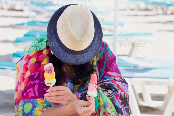 Summer style, colorful portrait of a woman on the beach with a hat holds ice cream, hidden face