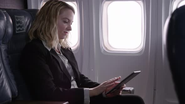 Young businesswoman using digital tablet on airplane