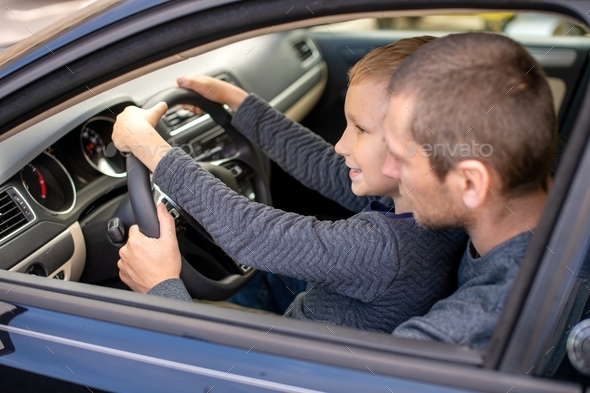 Dad shows his little son how to drive a car