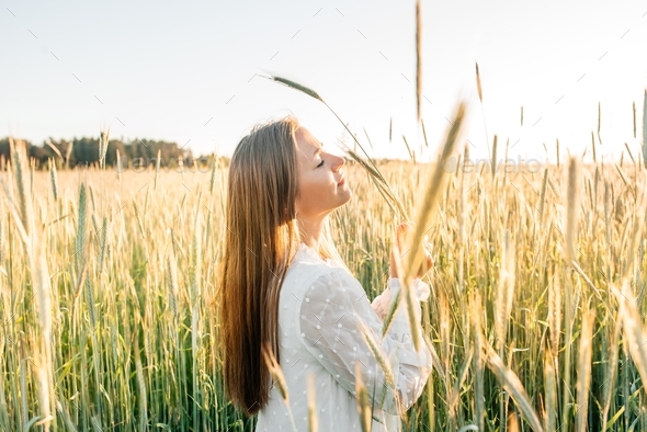 Girl in a field with ears of corn at sunset, sunny evening, emotional lifestyle. Hot Summer. Sunny