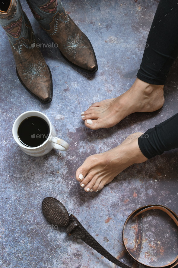 Woman sitting next to the cup of coffee and cowboy boots
