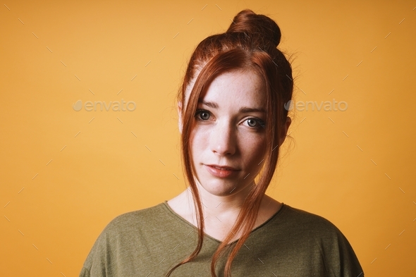 cool young woman with red hair messy bun hairstyle and loose strands at the front