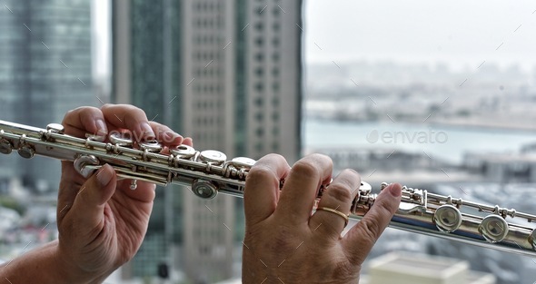 Music Woman playing flute on her high rise apartment building balcony with a panoramic view of the
