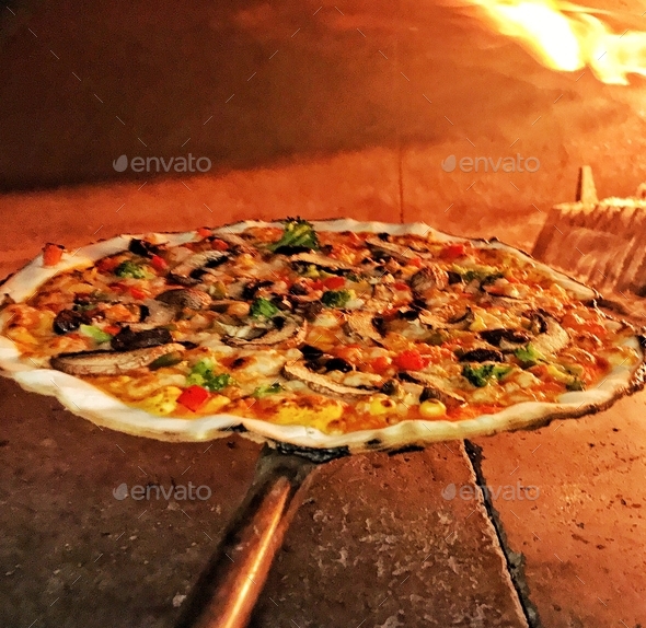 Cooking gluten free vegetarian pizza in a brick wood fired oven Stock Photo by spencerpa440