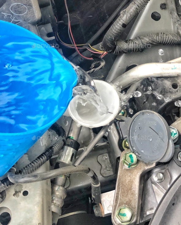 Automobile Maintenance Pouring water into windshield wiper dispenser to