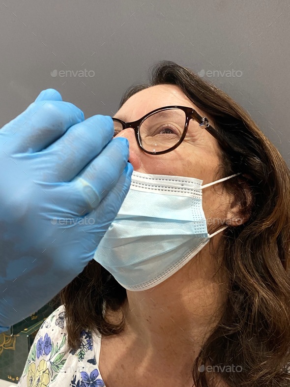 Middle aged baby boomer woman having her nose swabbed for a pcr test