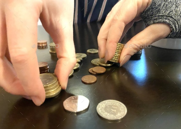 Counting Coins. Two women count money together on a table