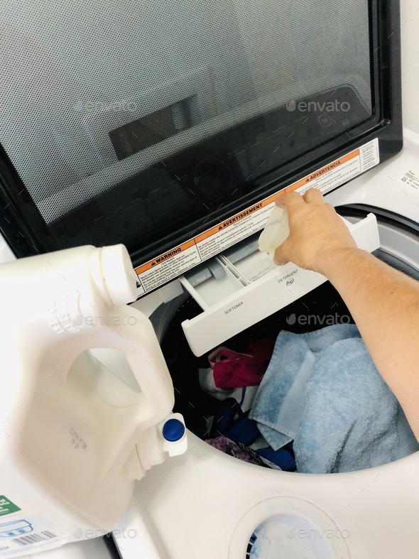 Putting detergent into the washing machine to do laundry. Stock Photo