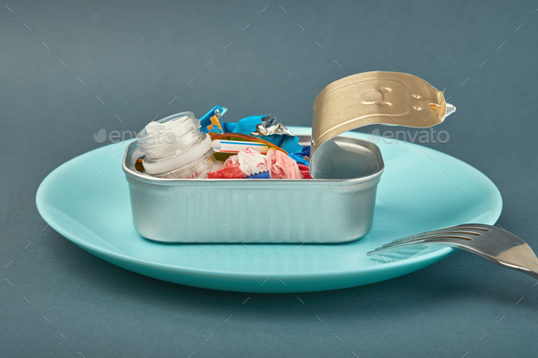 Open tin can on plate and fork. Plastic waste instead of fish. Ocean plastic pollution concept
