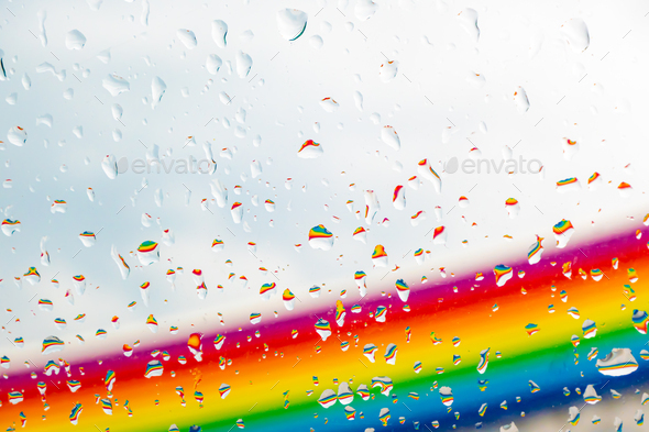 A rainbow behind a glass windows with water drops, Point of view, from behind the glass with drops.