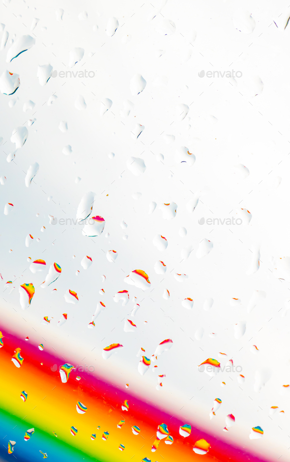 A rainbow behind a glass windows with water drops, Point of view, from behind the glass with drops.