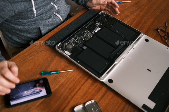 DIY project: man replacing laptop computer parts using how-to video