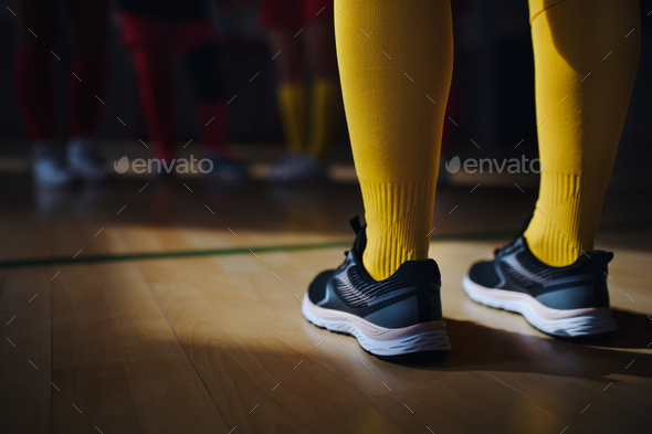 Close up of womans legs in knee socks and trainers in front of floorball mach in gym.
