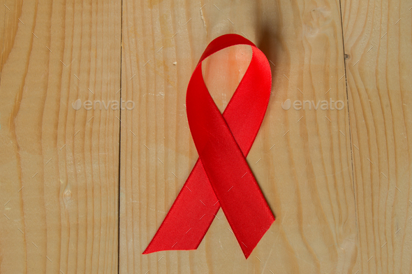 Awareness red ribbon on wood background: world day fight against AIDS, promotions to public support