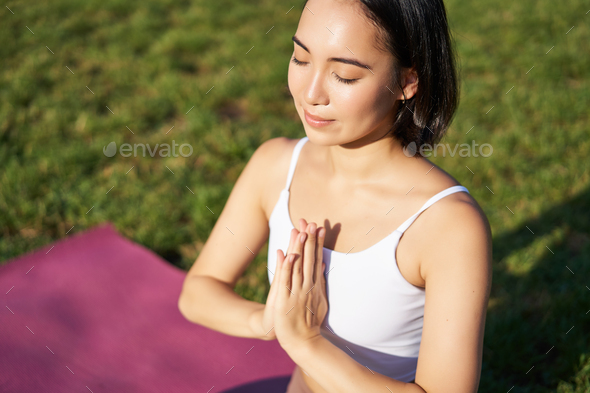 Portrait of young mindful woman, practice yoga, exercising, inhale and exhale on fresh air in park