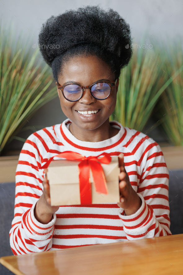 african American woman gives or receives a gift. a happy millennial woman with a cardboard box