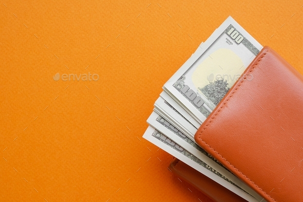 100 dollar in wallet on orange paper background