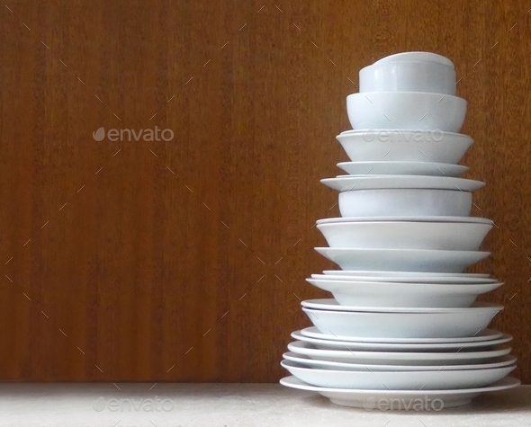Stack of white plates and crockery on table with space for text overlay