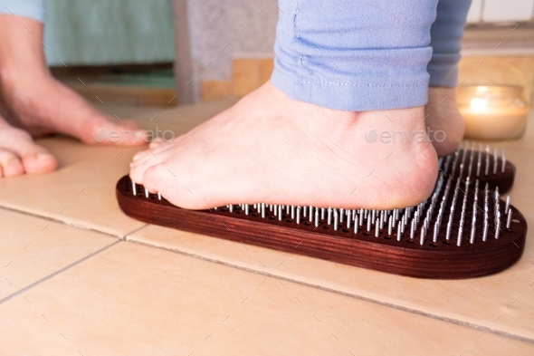 woman's feet stand on sadhu board at nail therapy during nailing. filling with energy.Pain, trials,