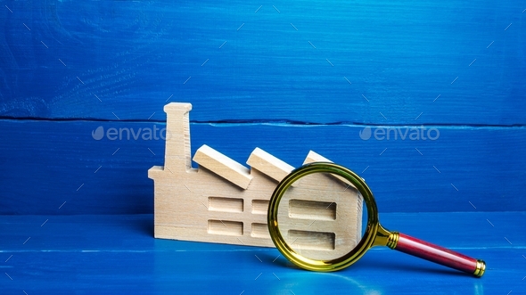 Figurine of an industrial factory plant and a magnifying glass
