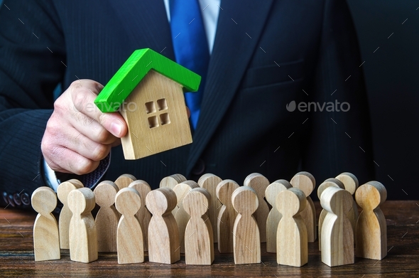 A man holds a house above a crowd of people.  - Stock Photo - Images
