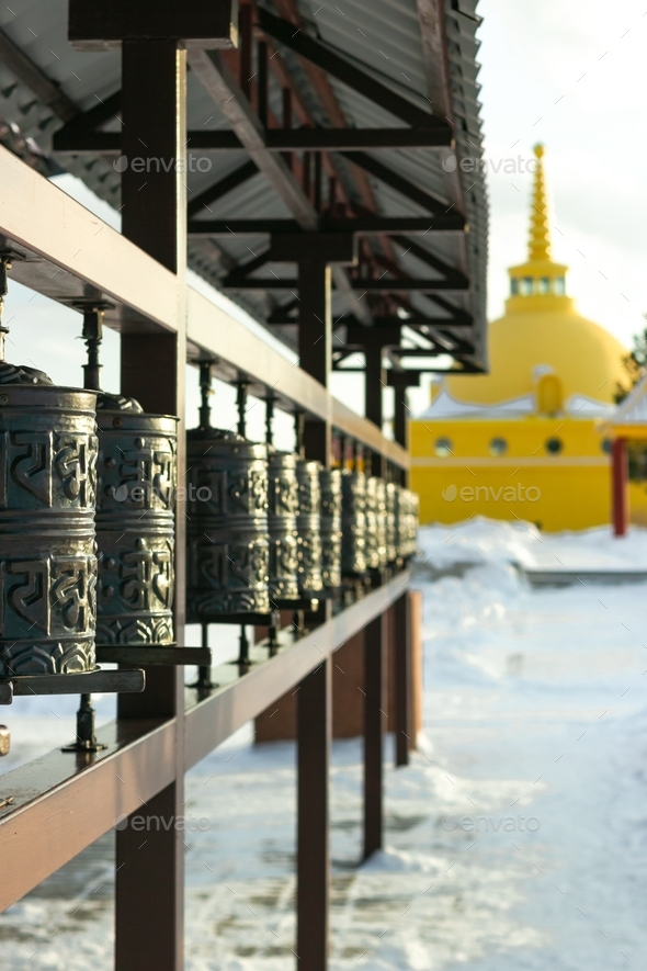 Traditional spinning prayer wheels with tibetan holy sacred shrine mantras at snowy temple