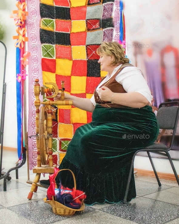  woman in national German clothes spins wool on a spinning wheel, national German traditions
