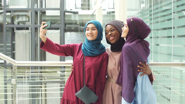 Group of Four Multiethnic Muslim Women in Traditional Hijab Take Selfie in Mall