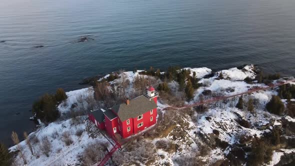 Red Lighthouse located in Marquette, Michigan in winter with rotating drone shot. alt