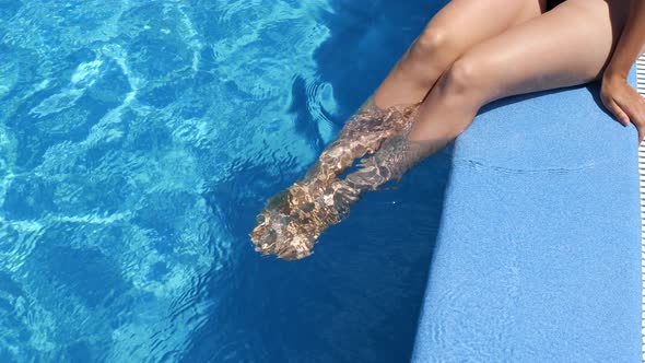 Slow motion footage of a woman sitting in a pool, enjoying the sun, and swimming in the pool. alt
