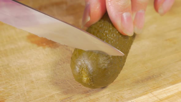 Pickled cucumber cutting piece with knife on wooden board 4K 2160p UHD footage - Gherkin piece on wo alt
