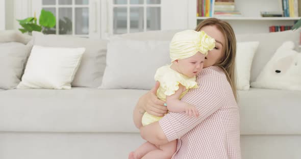 Young Mother Blonde Holding a Newborn Baby in Her Arms Indoors