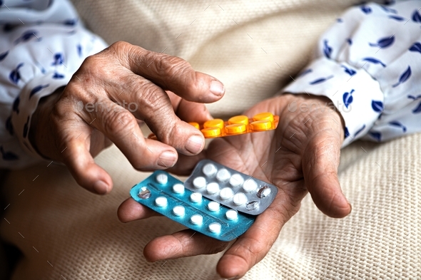 Many pills in senior woman hands. Painful old age. Caring for health of the elderly