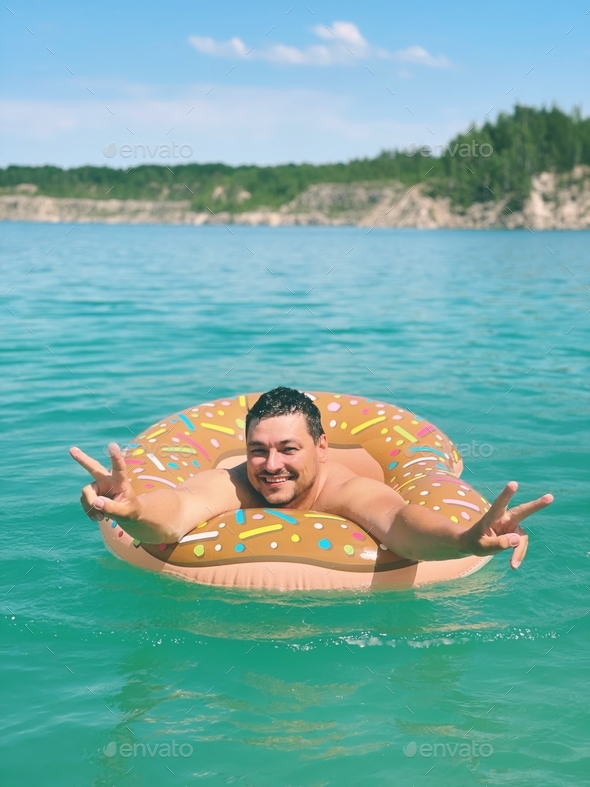 the guy swims with an inflatable ring in turquoise water