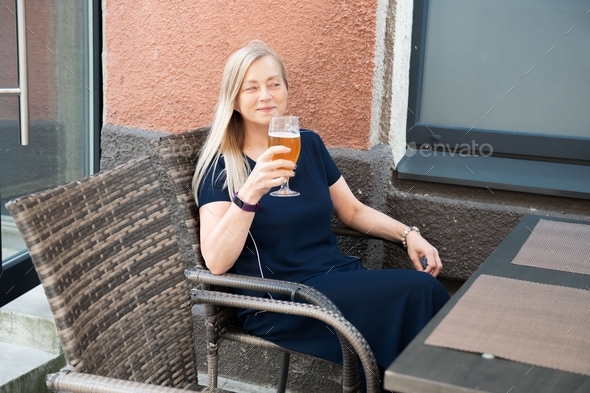 Beautiful Caucasian woman enjoying a fresh draft beer outside on sidewalk cafe