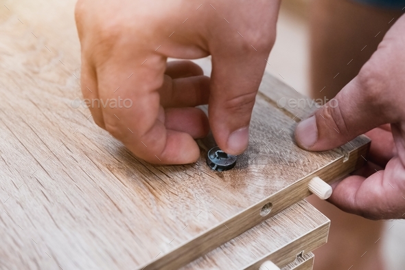 A close-up of a man\'s hand assembling furniture according to the instructions. Carpentry,