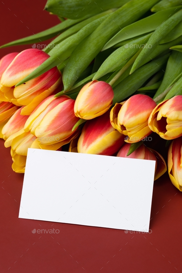 Clean minimal business card mockup with bouquet of tulips on a burgundy background. Greeting card