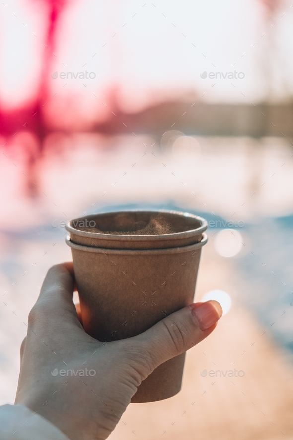 Womans hand with paper cup of coffee in winter snow background ...