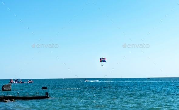 colorful rainbow parachute behind a boat over the blue sea summer activities Parasailing