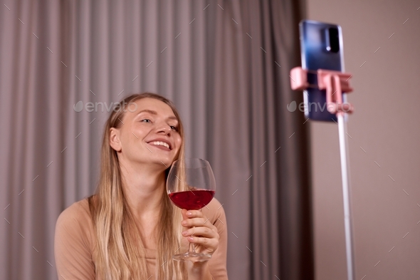 woman drinking wine and using smartphone for online meeting with family or boyfriend remotely