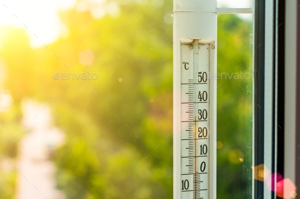 The thermometer outside the window shows a very hot air temperature, heated  by the rays Stock Photo by skaron2022