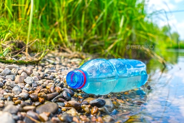 The problem of environmental pollution with plastic. A plastic bottle discarded on the riverbank - Stock Photo - Images