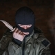Tired bandit in balaclava and holding a knife on a brick wall background - PhotoDune Item for Sale