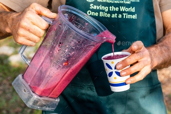 A man pouring a healthy berry smoothie into a paper cup. The drink ...