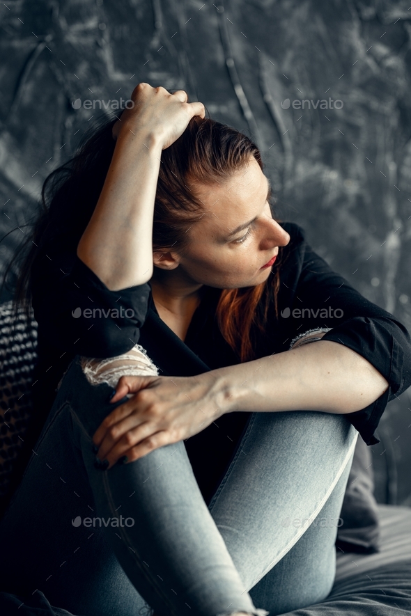 Young woman hugging her knees with her hands. Felling bad, sad, depressed. Mental health.