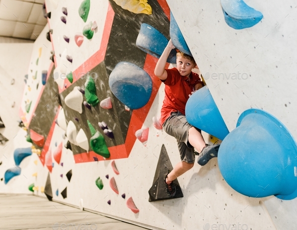 A Young Preteen Boy Boulders At A Climbing Gym To Stay Physically Fit 